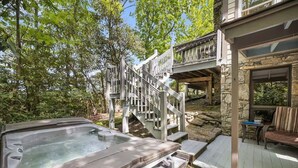 Ein Whirlpool, eine Holzterrasse, Steinwände und ein Sitzbereich im Freien.