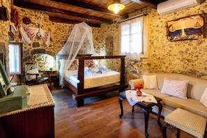 A traditional room with a bed, a sofa, a small table, and a decorative wall. - Kliton Villa (5GH7+85F Dhrimiskos, Greece)