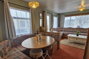 A cozy room with a round table, a sofa, and a small cabinet. - Palm Court - 3 Bed, Heated Pool, Parking, Nr Beach (Par)