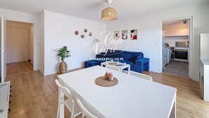 Un apartamento moderno con comedor, sala de estar con un sofá azul y cocina.