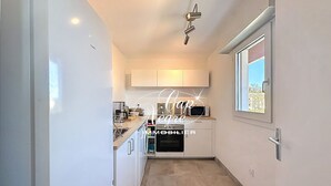Una cocina estrecha con armarios blancos, un microondas y una ventana con vistas.