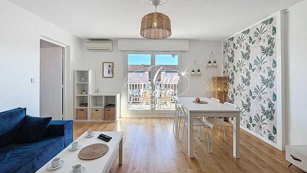Una sala de estar moderna con un sofá azul, una mesa de centro blanca y un comedor con sillas y mesa blancos.