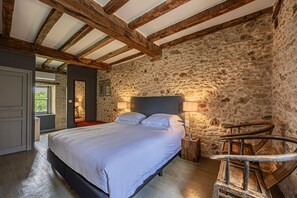 A bedroom with a stone wall, wooden beams, a bed, bedside lamps, and a spiral staircase. - Holiday Home 'Le Mas' with Private Pool, Private Terrace and Wi-Fi (Sainte-Croix)