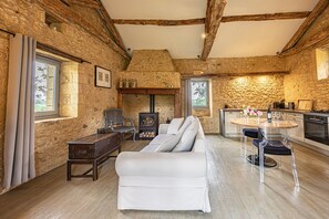 A rustic stone interior with a sofa, wooden table, and kitchen area. - Holiday Home 'Le Mas' with Private Pool, Private Terrace and Wi-Fi (Sainte-Croix)