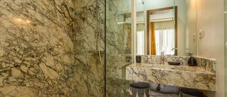 A bathroom with a marble shower and a vanity with a mirror.