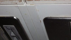 Un gros plan d’un mur recouvert de carreaux blancs, présentant des signes d’usure et de peinture écaillée.