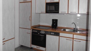 A compact kitchen with white cabinets, a microwave, a coffee maker, and a dishwasher. - At the meadow (Kuchelmiß)