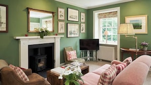 A living room with a fireplace, television, and comfortable seating. - Miniature Castle Surrounded by Woodland on a Scottish Estate (Leven)