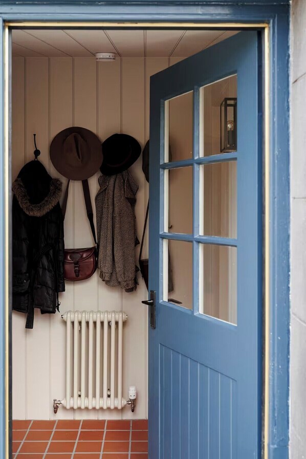 A blue door with a white radiator and hats hanging on the wall.