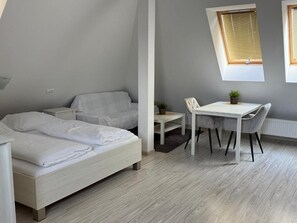 Een slaapkamer met een bed, een stoel, een tafeltje en een raam.