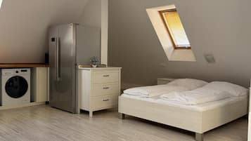 Ein Schlafzimmer mit Bett, Waschmaschine, Kühlschrank und Dachfenster.