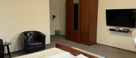 Una habitación de hotel con cama, televisión, armario y una silla.