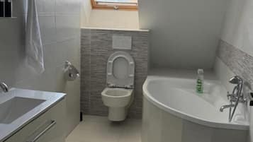 A modern bathroom with a toilet, sink, and bathtub.