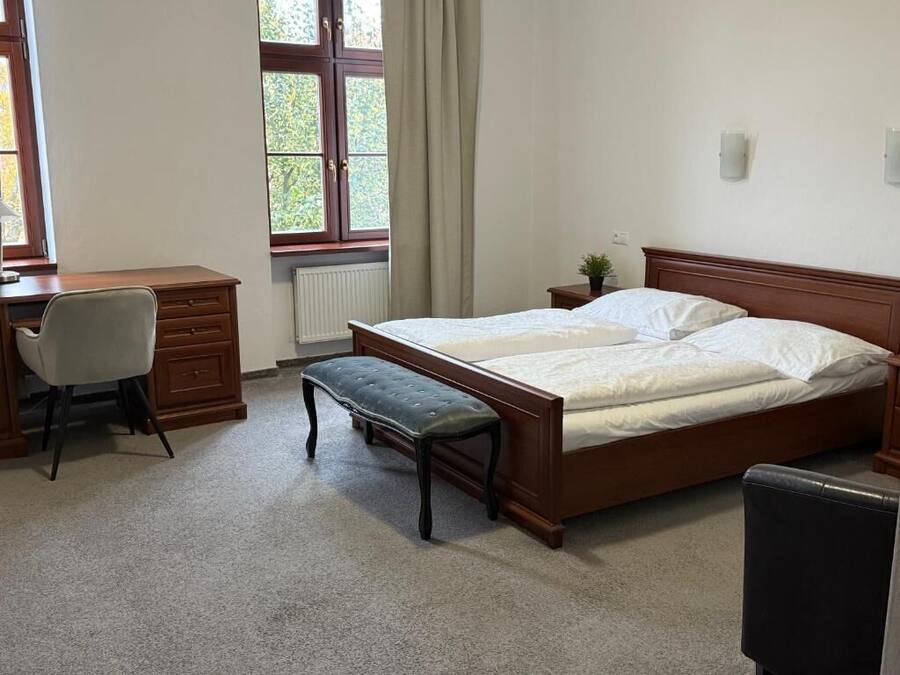Ein Schlafzimmer mit einem hölzernen Bett, einem Schreibtisch, einem Stuhl und einer Heizung.