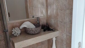 Ein Badezimmer mit Marmorwaschbecken, einem großen Spiegel und einer Duschkabine.