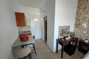 Cocina compacta con comedor, una pared de acento de piedra y una pequeña mesa con objetos decorativos.
