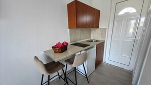 Eine kompakte Küche mit Arbeitsplatte, zwei Barhocker, einem Spülbecken und Holzschränken.