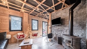 Ein Holzblockhaus-Innenraum mit Steinwand, Kamin und an der Wand montiertem Fernseher.