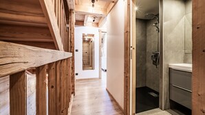 Un pasillo de madera que conduce a un baño con ducha y lavamanos.
