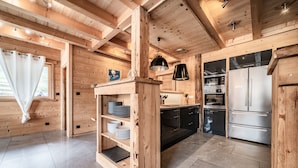 Un interior de madera con cocina, que incluye un refrigerador, horno y estantes.