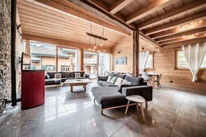 A spacious living area with wooden beams, a sofa set, a coffee table, and a red cabinet. - Chalet "Stéphane": Mountain View, Private Terrace & Wi-Fi (Châtel)