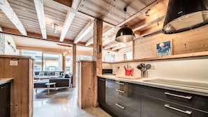 Cocina moderna con armarios oscuros, encimera de acero inoxidable y una lámpara colgante.