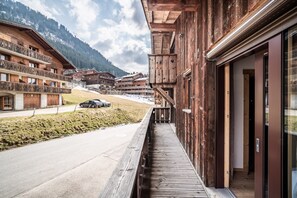 Ein Holzbauten mit Balkonen, eine gepflasterte Straße und eine gebirgige Kulisse.