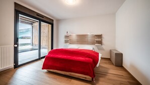 Een slaapkamer met een bed, een raam met zonwering, een radiator en een balkon.