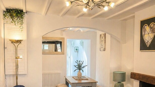 Een gezellige woonkamer met een bank, een open haard, een eettafel en een keuken in de achtergrond.