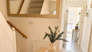 Een eethoek met een houten tafel, bankzitplaatsen, een vaas met bloemen, een spiegel en een trap.