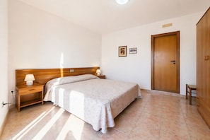 Una camera da letto con un letto, comodini, un'armadio in legno e una porta.