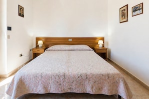 A neatly made bed with a floral bedspread, two bedside lamps, and a wooden headboard.