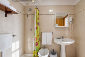A bathroom with a shower, toilet, sink, and a mirror.