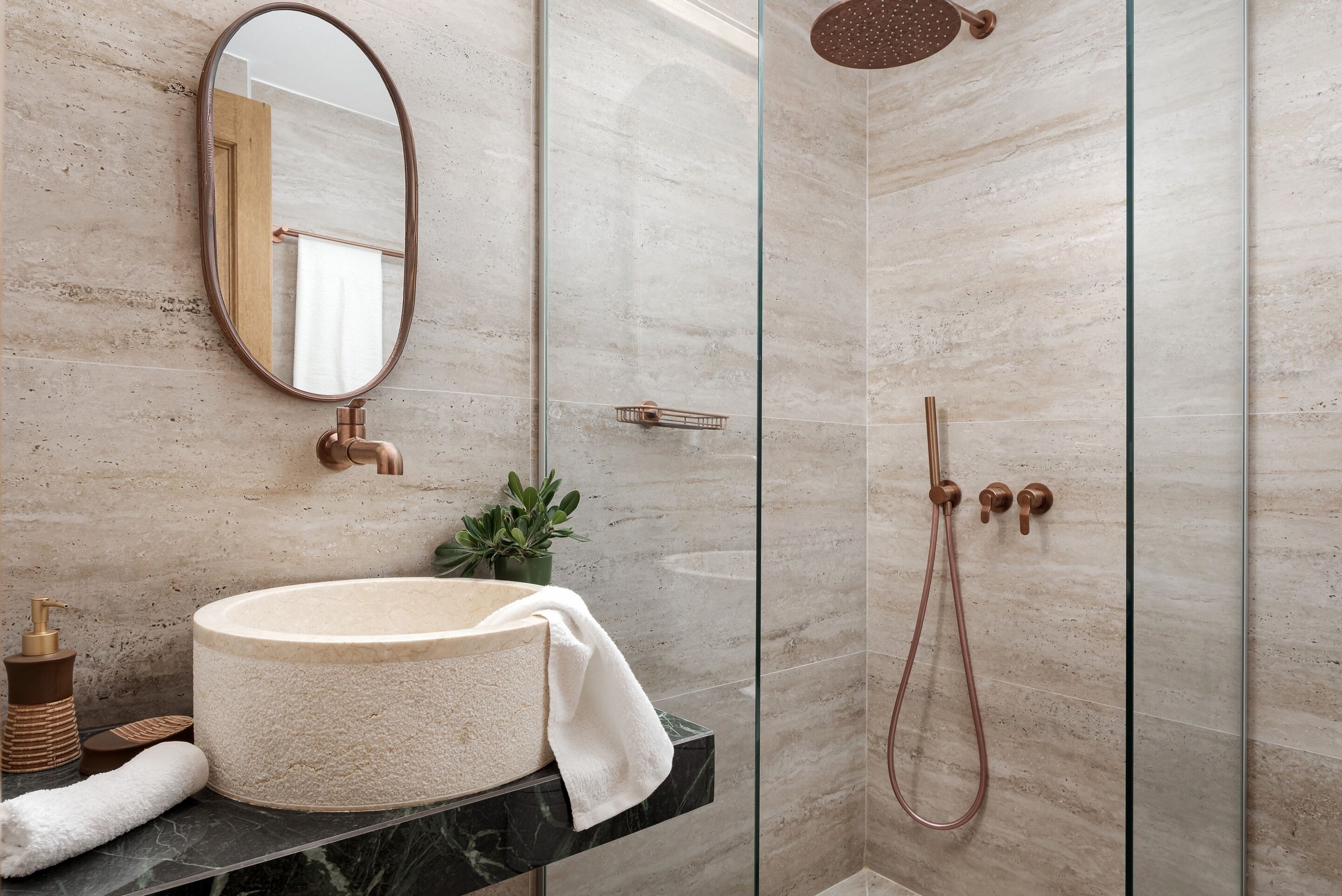 A bathroom with a round sink, a mirror, a shower, and a towel.