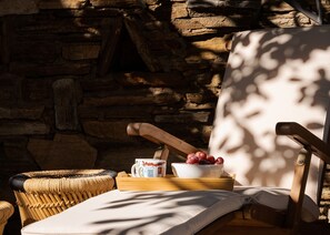 A wicker chair with a cushion, a wooden tray with a bowl of grapes, and a white mug with a blue design. - Seashore Villas Tinos (Tinos)
