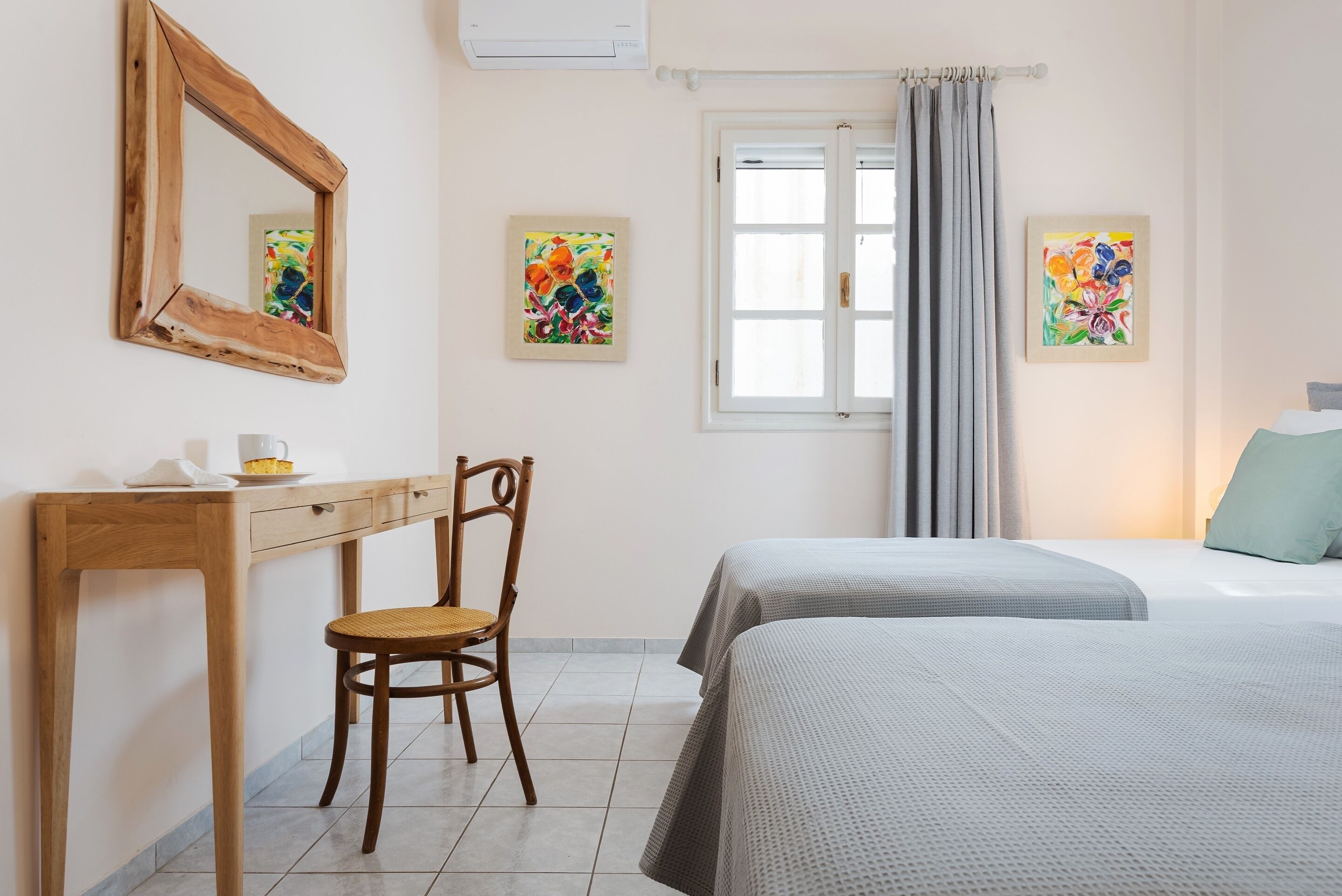 A bedroom with a bed, a wooden desk, a chair, and two paintings on the wall.