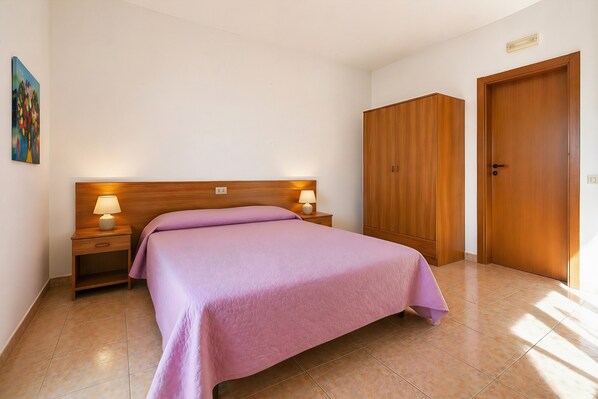 A bedroom with a bed, nightstands, a wooden wardrobe, and a door. - San Michele - 25 - Bed & Breakfast with Sea View, Wi-Fi and Air Conditioning (Mattinata)