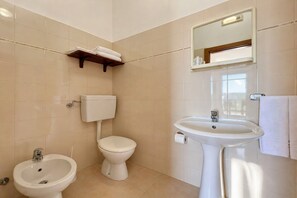 A bathroom with a toilet, bidet, sink, mirror, towel rack, and shelf. - San Michele - 25 - Bed & Breakfast with Sea View, Wi-Fi and Air Conditioning (Mattinata)