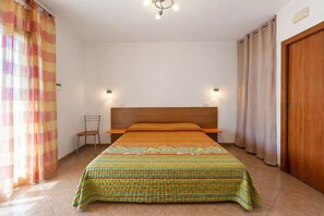 Une chambre à coucher avec un lit, une chaise, une tête de lit en bois et des rideaux.