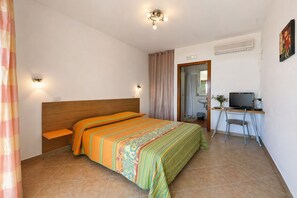 A bedroom with a bed, a desk with a computer, a chair, and a shower area. - San Michele - 4 - Bed & Breakfast with Sea View, Wi-Fi and Air Conditioning (Mattinata)