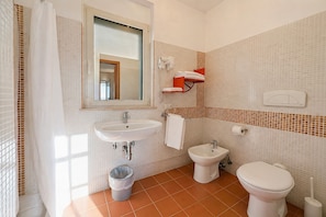 Une salle de bain équipée d’un lavabo, d’un bidet, de toilettes et d’un miroir.