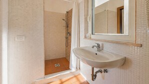 Een badkamer met een douche, wastafel en spiegel.