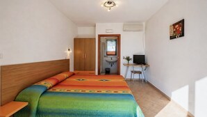 A bedroom with a bed, a desk, a chair, a television, and an air conditioning unit. - San Michele - 5 - Bed & Breakfast with Sea View, Wi-Fi and Air Conditioning (Mattinata)