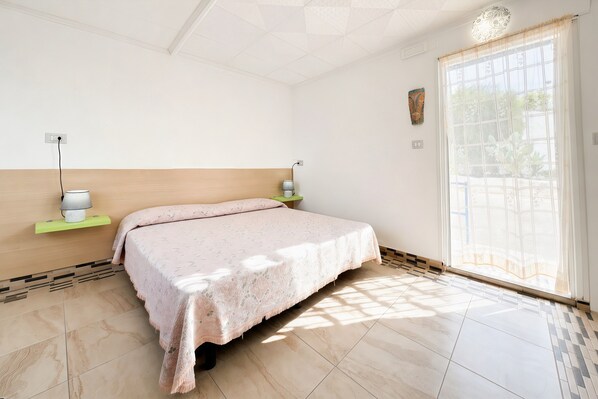 Un dormitorio con cama, lámparas de noche, una ventana con vistas y una obra de arte colgada en la pared.