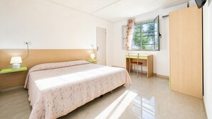 Une chambre à coucher comprenant un lit, des tables de chevet, un bureau, une chaise, une armoire et un téléviseur.