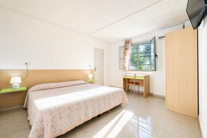 Ein Schlafzimmer mit Bett, Nachttischen, Schreibtisch, Stuhl, Kleiderschrank und Fernseher.