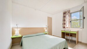 Una camera da letto con un letto, comodini, una scrivania, una sedia e una finestra con tende.