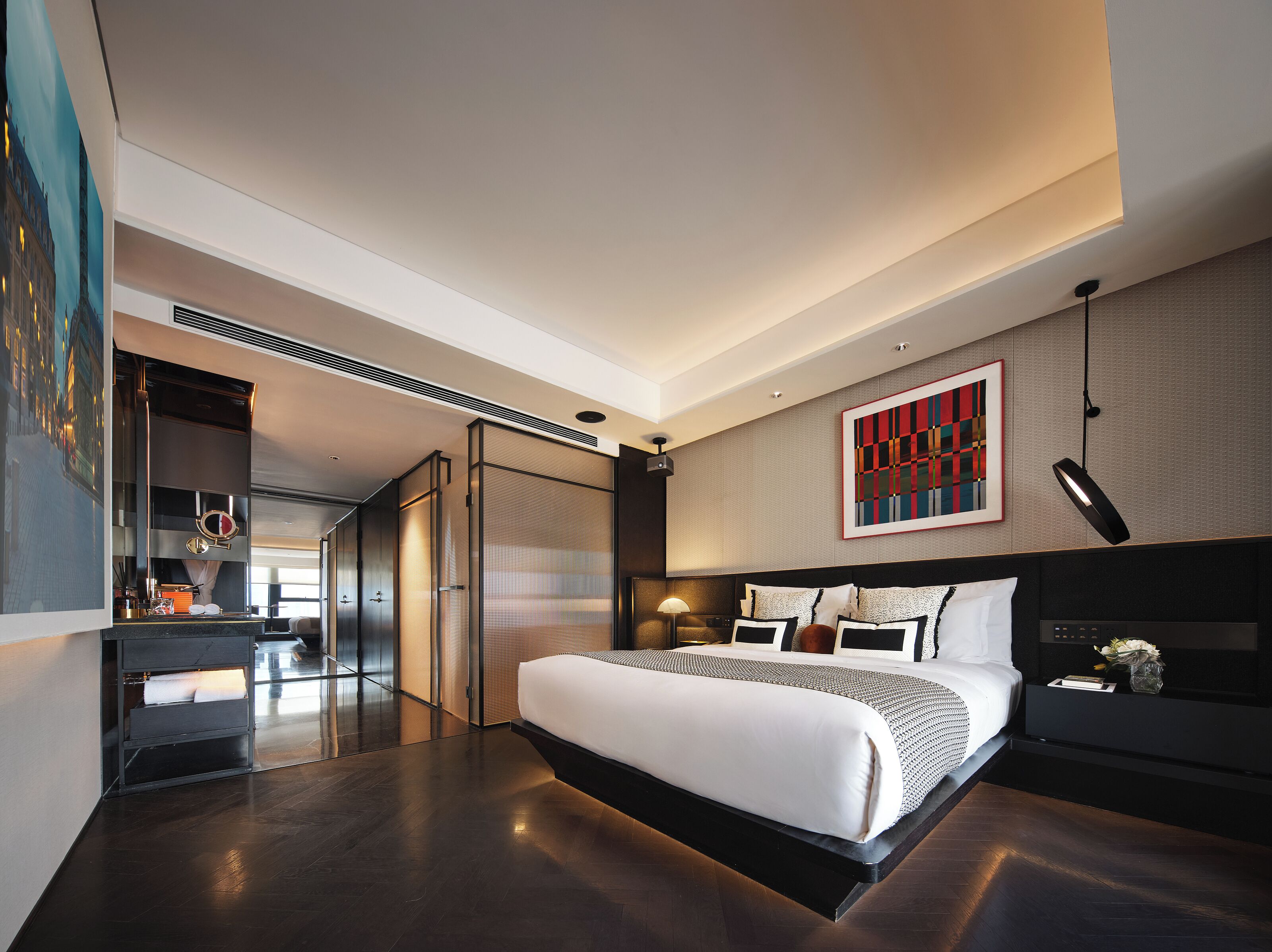 Ein modernes Hotelzimmer mit einem großen Bett, einem Schreibtisch und einem Wandbild.