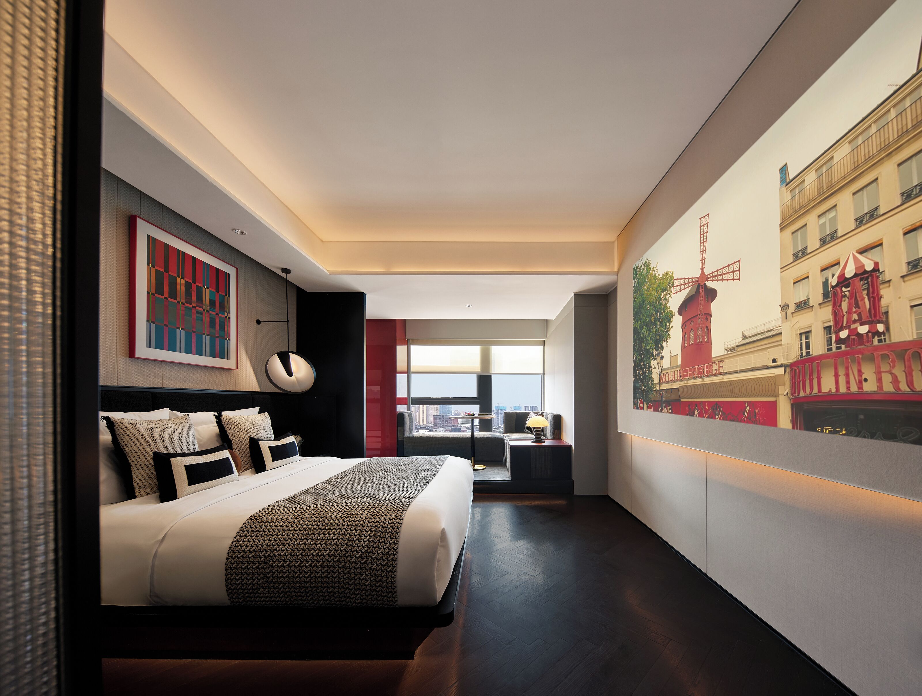 A modern hotel room with a large bed, a cityscape mural, and a view of the Eiffel Tower.