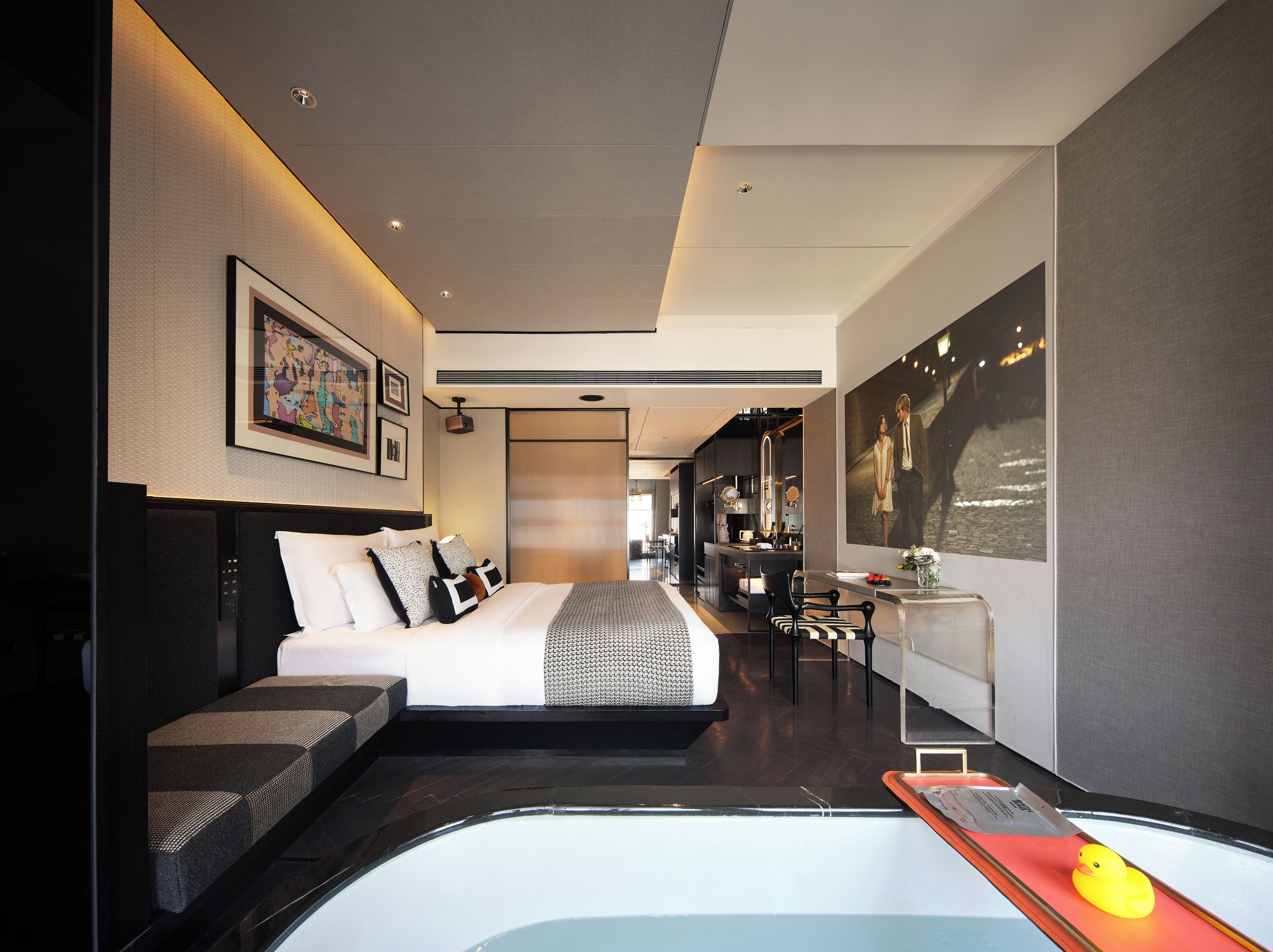 Une chambre d’hôtel moderne dotée d’un grand lit, d’un petit bureau, d’un coin salon et offrant une vue sur la ville.